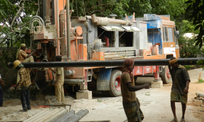 A group of men wearing work clothes and operating a huge vehicle for domestic borewell drilling.